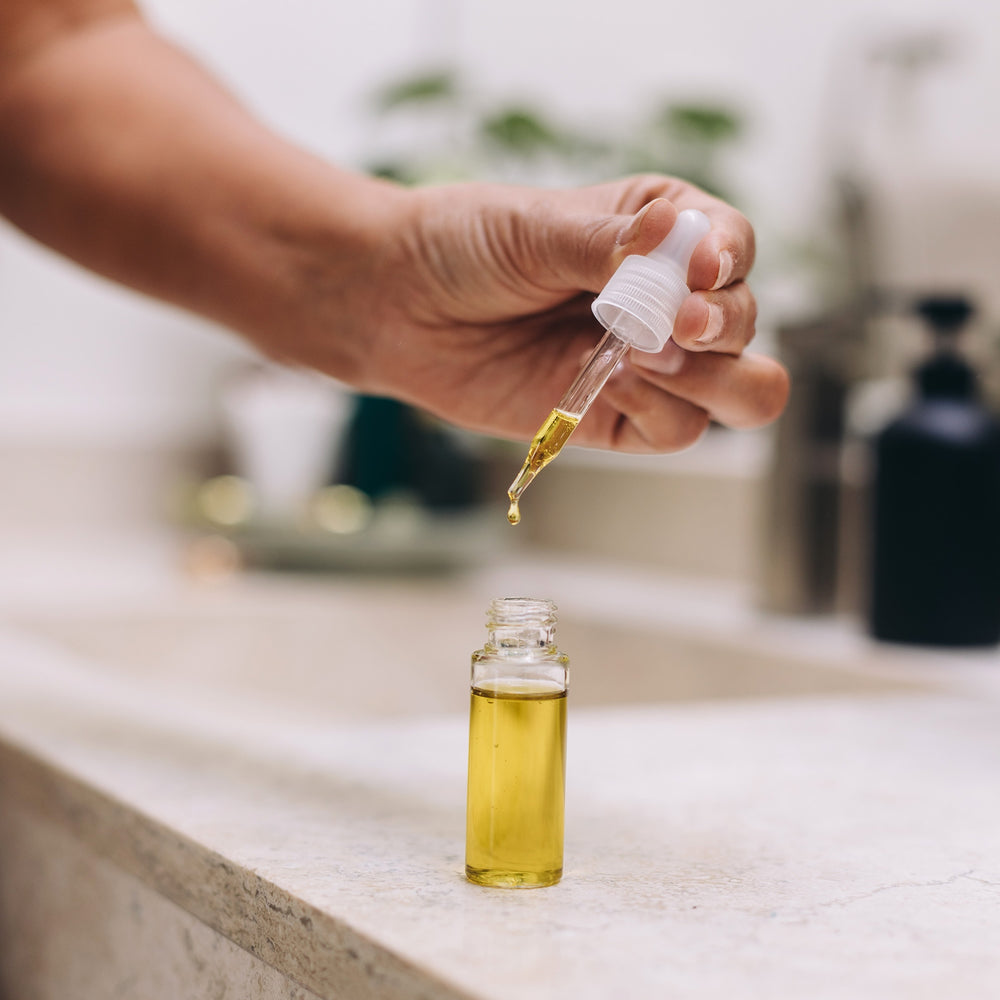 image of a hand holding a dropper full of face or body oil from a clear bottle